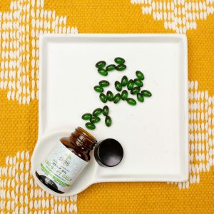 CBD oil capsules in a bottle on a white tray over an orange patterned fabric. Ideal for health and wellness themes.